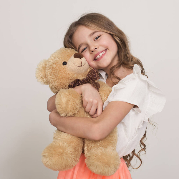 Kindheit, Spielzeug und Einkaufskonzept. entzückendes kleines Mädchen umarmt ihr Lieblingsspielzeug - Teddybär - Foto, Bild