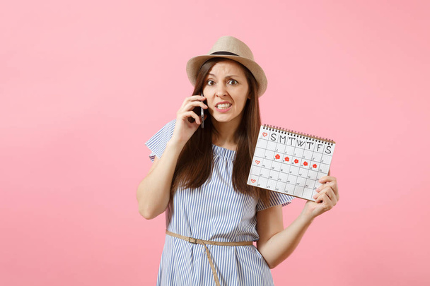 Θλιβερή συγχέεται γυναίκα μιλάει στο κινητό τηλέφωνο, κρατώντας ημερολόγιο περίοδοι για τον έλεγχο της εμμήνου ρύσεως ημέρες απομονώνονται σε φωτεινό τείνοντας ροζ φόντο. Ιατρικές, περίθαλψης, γυναικολογικές έννοια. Χώρο αντίγραφο - Φωτογραφία, εικόνα