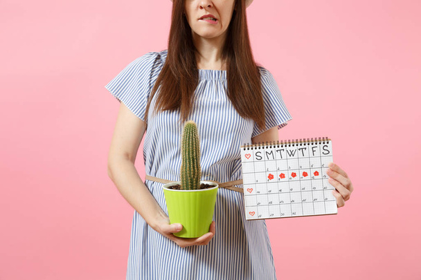 Donna malata triste in abito blu con cactus verde, calendario dei periodi per controllare i giorni mestruali isolati su sfondo rosa. Medico, sanitario, ginecologico, concetto di dolore allo stomaco. Copia spazio
 - Foto, immagini