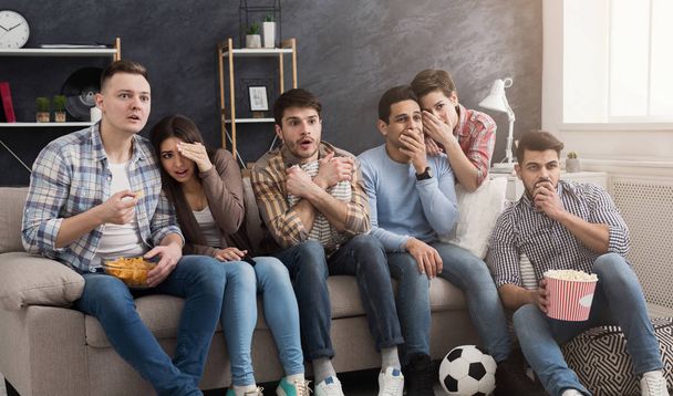 Shocked multiethnic friends watching movie at home - 写真・画像