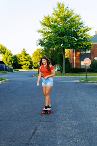 Fille skateboard sur l'intestin heureux jeune adolescent équitation skateboard en plein air dans une aire de stationnement
. - Photo, image