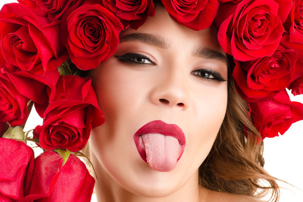 beautiful portrait girl with roses on head and out tongue  - Photo, Image
