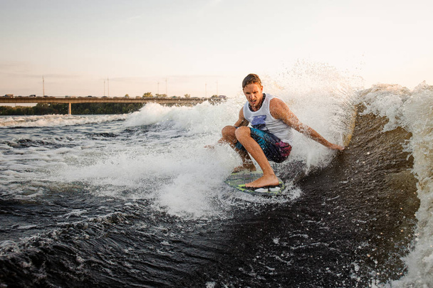 Nuori aktiivinen mies ratsastus Wakeboard taivutettu jalat korkea aalto moottorivene, ottaa terve kesäaika
 - Valokuva, kuva