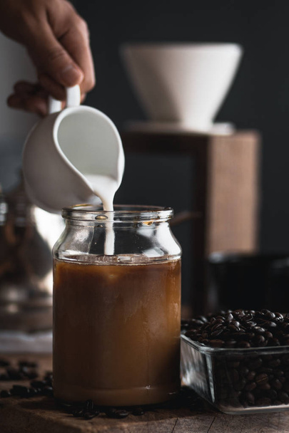 café Em uma garrafa de vidro, gotejamento de café, mão segurando uma chaleira Gotejamento de café No quarto, café preto em vidro
 - Foto, Imagem