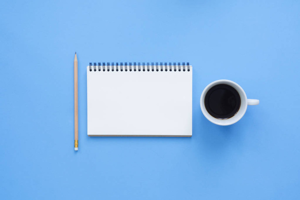 Office desk working space - Flat lay top view mockup of a working space with white blank notebook page, coffee cup on blue pastel background. Pastel blue color background space concept. - Φωτογραφία, εικόνα