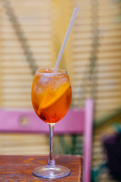 Aperitif-Cocktail bestehend aus Prosecco, Aperol und Sodawasser, steht im Weinglas auf einem Holztisch in der Bar. Aperol Spiritz Cocktail mit mehreren Eiswürfeln und Orangenscheiben. - Foto, Bild