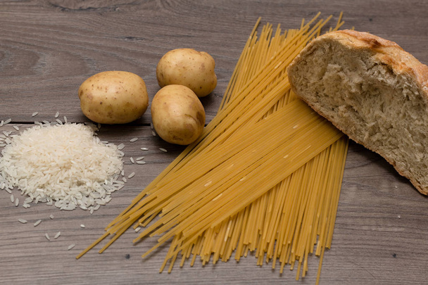 Spagetti, a rizs, a burgonya és a kenyér, egy fából készült asztal - Fotó, kép