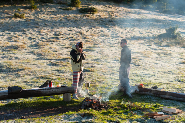 Two friends in the mountains in the morning at the fire play the harmonica - Fotoğraf, Görsel