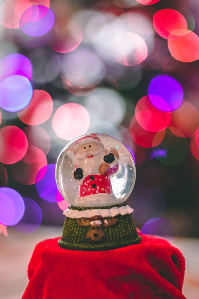 Санта стеклянный шар украшения с рождественскими огнями на заднем плане вне фокуса
 - Фото, изображение