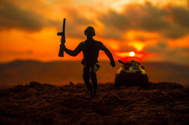 War Concept. Military silhouettes fighting scene on war fog sky background, World War Soldiers Silhouettes Below Cloudy Skyline at sunset. Soldier trying to escape from tank - Photo, Image