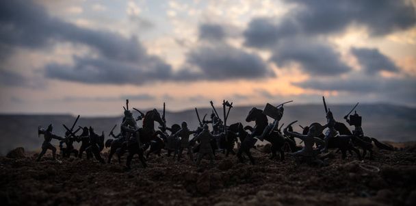 Cena de batalha medieval com cavalaria e infantaria. Silhuetas de figuras como objetos separados, luta entre guerreiros no pôr-do-sol fundo nebuloso. Foco seletivo
 - Foto, Imagem