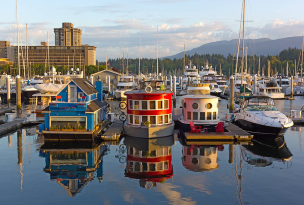 VANCOUVER, CANADA - Boat houses on the water of Coal Harbour Marina at sunrise. City panorama with floating boathouses, forest, and mountain ridges on the horizon. - Φωτογραφία, εικόνα