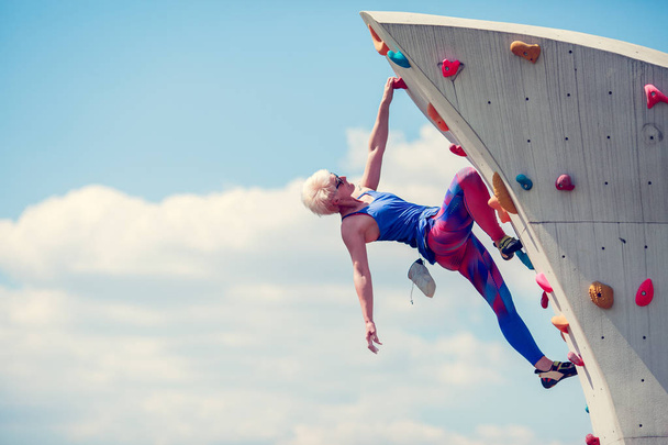 Picture from side of sports girl climbing on rocky summer day - 写真・画像