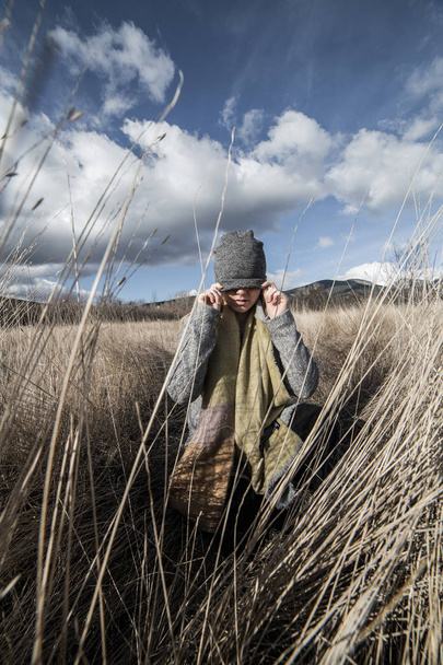 Woman in a dry wheat field with eyes covered with a gray cap - Photo, Image