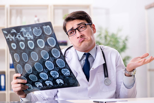 Mladý lékař prohlíží rentgenové snímky na klinice - Fotografie, Obrázek