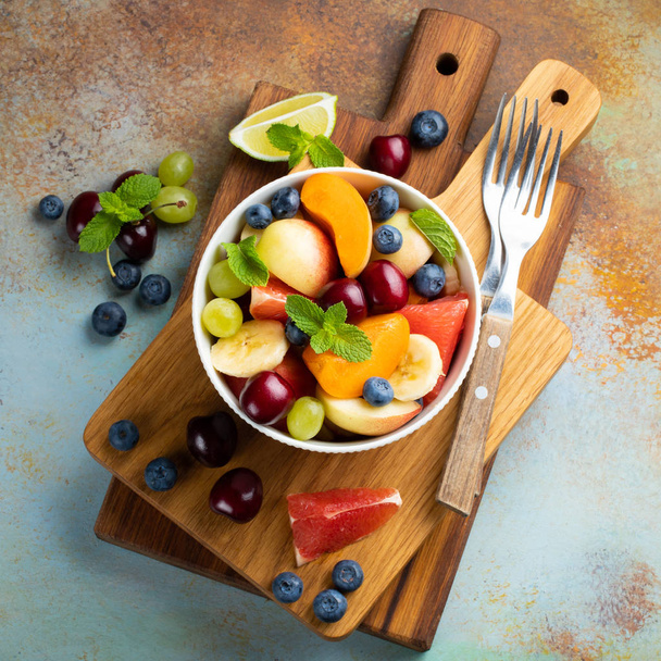 Bowl of healthy fresh fruit salad on a blue rusty background. Top view. - Photo, Image
