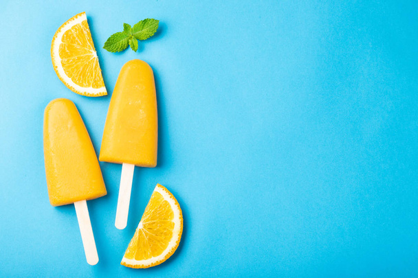 Orange popsicles with juice on a blue bacground. Ice pops, flat lay, top view with copy space. - Photo, Image