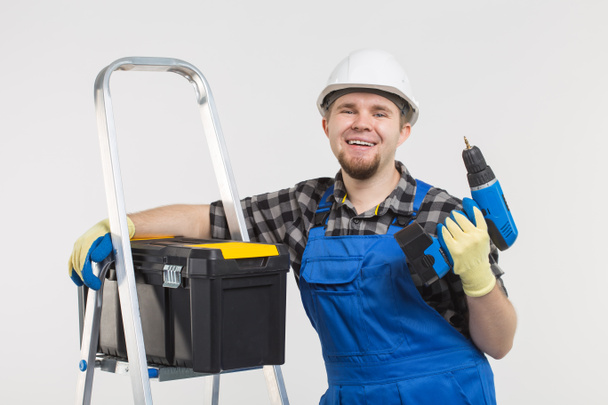 Portrait of handsome happy builder with skrewdriver on white background - Photo, Image