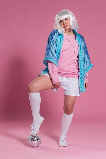 young woman with retro clothes listening to music and dancing against a pink background, studio shot - Photo, Image