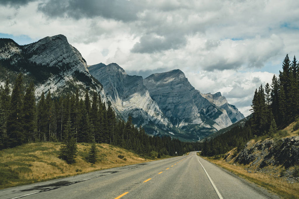 View of street highway with mountains and trees with blue sky and clouds. Banff National Park Canada Rocky Mountains. - Foto, afbeelding