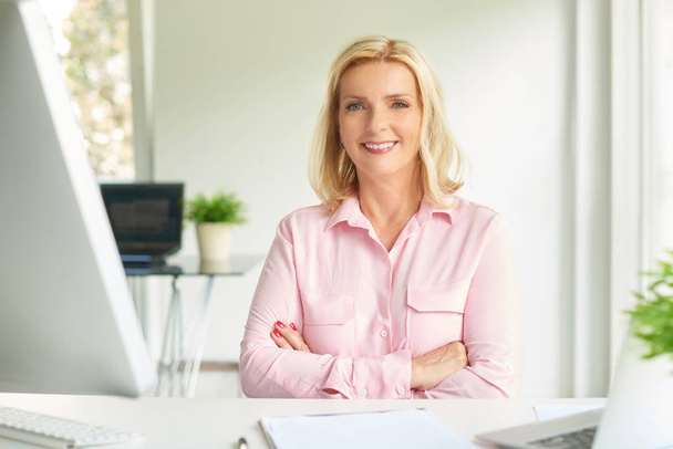 Portrait of smiling businesswoman sitting in light office - Fotografie, Obrázek