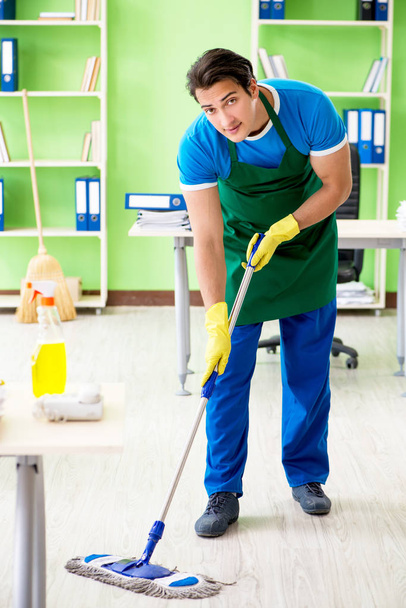 Masculino bonito profissional de limpeza fazendo esfregar no escritório - Foto, Imagem