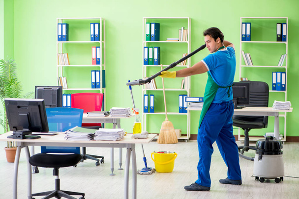 Schöner Mann putzt Büro mit Staubsauger - Foto, Bild
