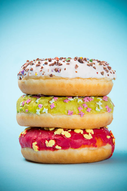 Tasty doughnuts on pastel blue background. - Фото, зображення