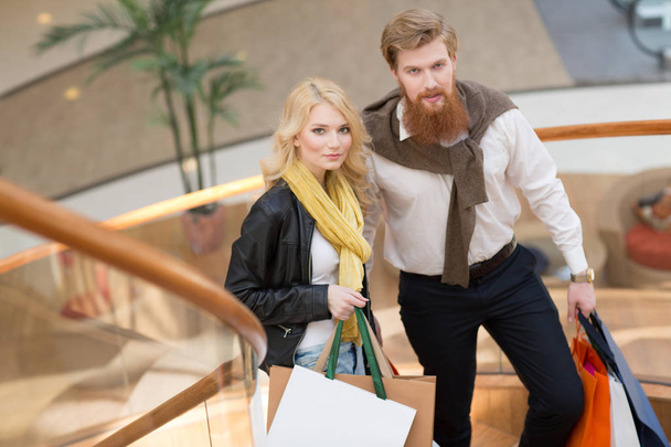 Happy beautiful young couple with shopping bags in mall - Foto, imagen