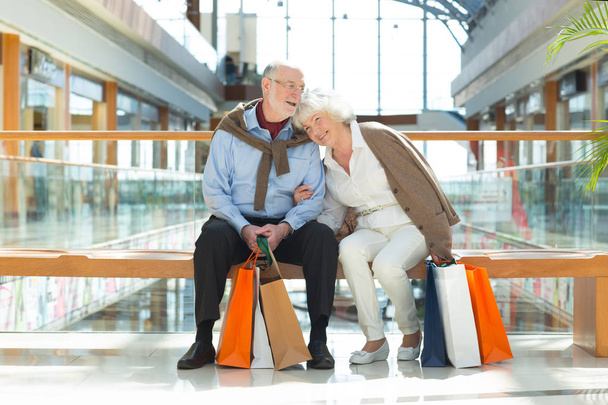 Senior couple sitting in shopping mall with gifts - Foto, Imagem