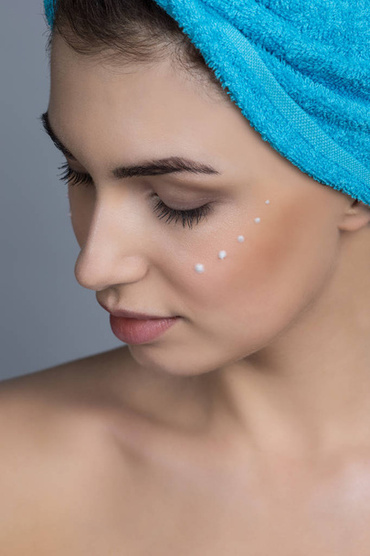 Beautiful woman with towel on head applying creme after shower - Zdjęcie, obraz