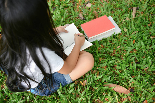Education Concepts. The girl is reading a book in the garden. Beautiful girl is seriously studying. Beautiful girls are happy learning. - Foto, Imagen