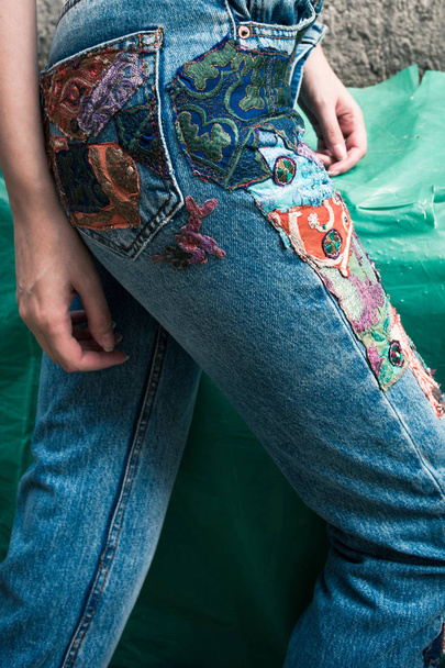 closeup of young woman in boho style blue jeans with colorful applications lower body outdoor - Фото, зображення