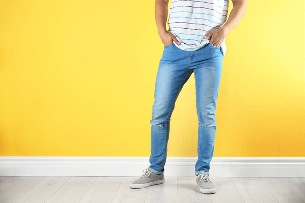Young man in stylish jeans near color wall - Foto, Imagem