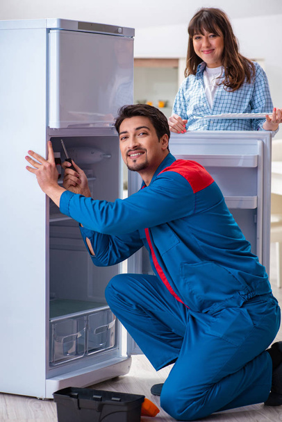 Adam müşteriyle buzdolabını tamir ediyor. - Fotoğraf, Görsel