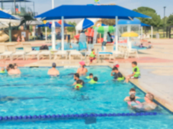 Blurred children and their parents enjoy swimming and water activities at community outdoor swimming pool. Healthy lifestyle, active parent, swim lesson activity, family vacation at aquatic center - Photo, Image