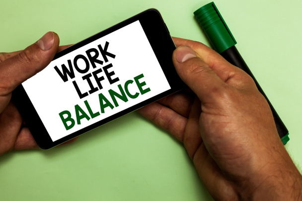 Schreiben Notiz zeigt Work-Life-Balance. Geschäftsfoto, das die Aufteilung der Zeit zwischen Arbeit oder Familie und Freizeit zeigt, menschliche Hand hält iPhone mit Texten, die grüne Markierung berühren - Foto, Bild