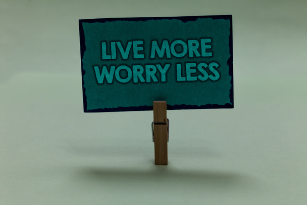 Пишу записку, показывающую Live More Worry Less. Иметь хорошее отношение мотивации быть небрежным наслаждаться жизни скрепки сцепление черная подкладка зеленая страница с контурами серый фон
 - Фото, изображение