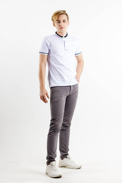 Handsome blond boy teenager in white shirt stands in white studio, full body - Photo, Image