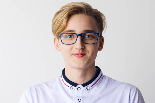 Handsome boy teenager in glasses and white shirt poses in white studio - Foto, Imagen