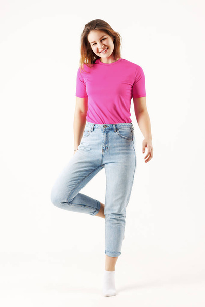 Girl teenager in pink t-shirt and jeans stands in white studio, full body - Fotografie, Obrázek