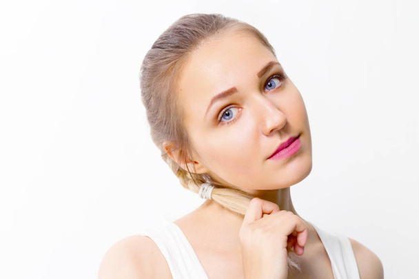 Beautiful blonde girl holds her braid in studio, close up portrait - Fotografie, Obrázek