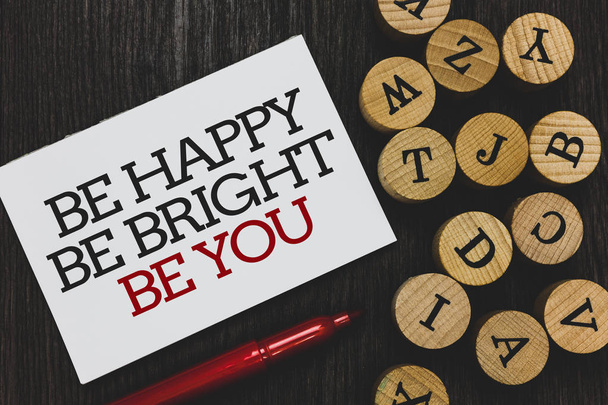 Signo de texto que muestra Be Happy Be Bright Be You. Foto conceptual Buena actitud de confianza en sí mismo disfrutar alegre papel escrito marcador rojo al lado de alfabetos leñosos redondos en la base de madera
 - Foto, imagen
