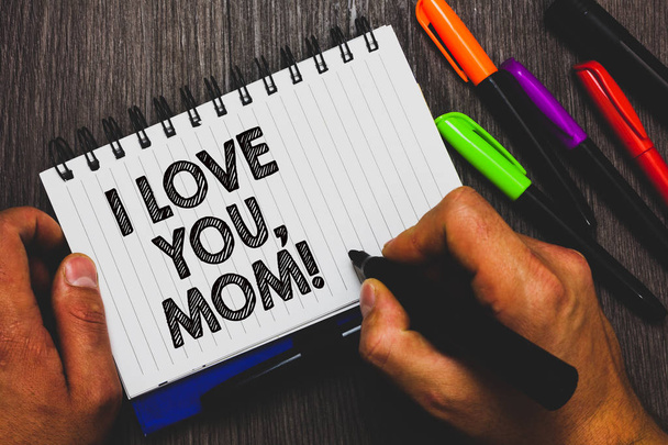 Ich liebe dich, Mama. Geschäftskonzept für liebevolle Botschaft emotionale Gefühle Zuneigung warme Erklärung Hand hält Stift und Papier Skizze Wörter in der Nähe liegen einige Stift auf holzigen Schreibtisch - Foto, Bild