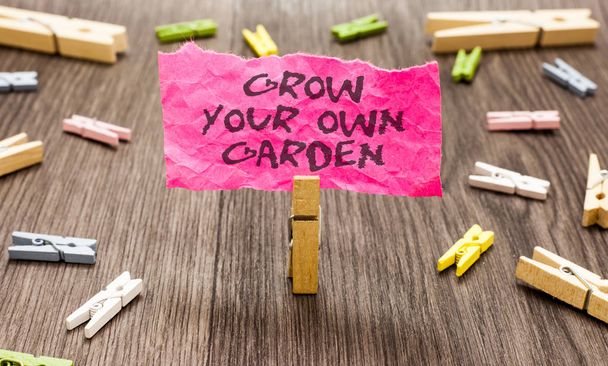 Conceptual hand writing showing Grow Your Own Garden. Business photo showcasing Organic Gardening collect personal vegetables fruits Paperclip hold pink note with texts many clips wooden floor - Photo, Image