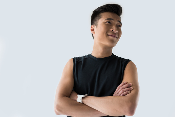 молодой улыбающийся азиатский спортсмен, стоящий со скрещенными руками, изолированный на сером фоне
  - Фото, изображение