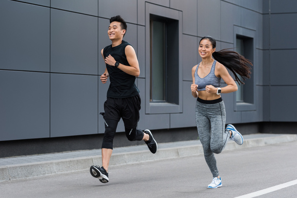 都市のストリートで実行しているアジアの女性と男性の選手の笑顔  - 写真・画像