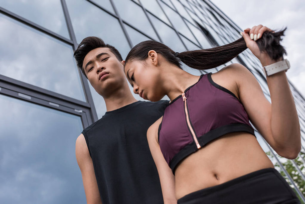 low angle view of serious asian sportsman and sportswoman standing at urban street - Foto, Imagen