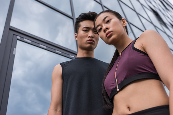 low angle view of serious asian sportsman and sportswoman looking at camera at urban street - Fotoğraf, Görsel
