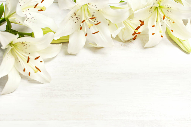 Rahmen aus weißen Lilien isoliert auf einem weißen Holzhintergrund Draufsicht. Blumen Lilie schöner Strauß weiße Blumen blumiger Hintergrund Konzept Urlaub - Foto, Bild